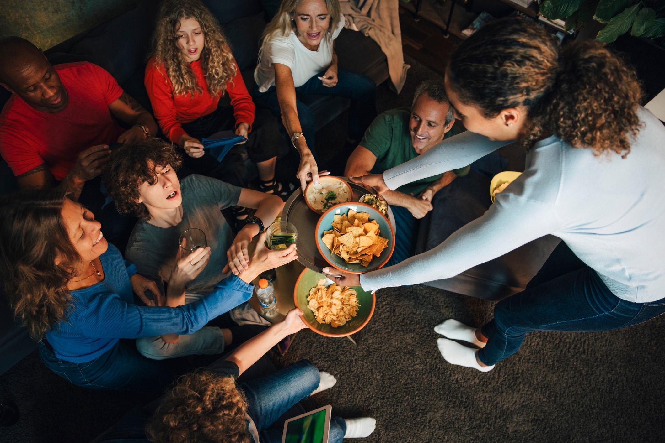 Famille qui mange des croustilles et des collations à la maison, illustrant des moments d’achat du quotidien influencés par les médias de détail